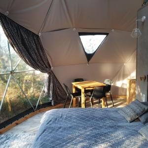 a bedroom with a bed and a table in a tent at Glamping Podniebny in Borsk