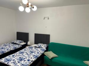 a room with two beds and a green couch at Studio pod Orzechem in Zbąszyń