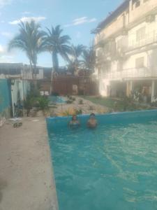 two people in a swimming pool next to a building at Hostel Angeles del Mar in San Antonio