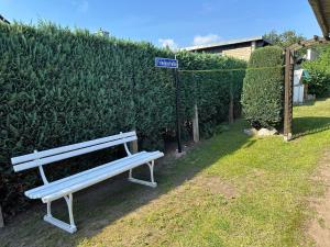 a white park bench sitting next to a hedge at Windrose in Korswandt