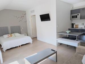 a white bedroom with a bed and a table at Studio détente proche Sanctuaires in Lourdes
