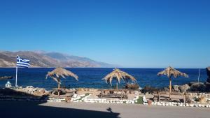 a beach with some straw umbrellas and the ocean at Elafonisos Rooms in Kefálion