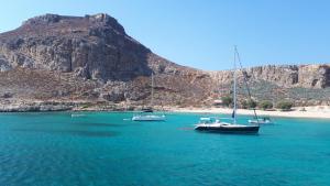 three boats sitting in the water near a mountain at Elafonisos Rooms in Kefálion