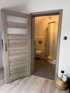 a bathroom with a wooden door and a toilet at Szum Morza in Wrzosowo +37 photos