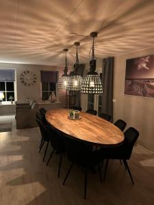 a dining room with a wooden table and black chairs at Groepsaccomodatie Tzummarum in Tzummarum