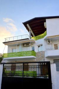 a white house with a black gate in front of it at Guest House Vila Krejs in Durrës