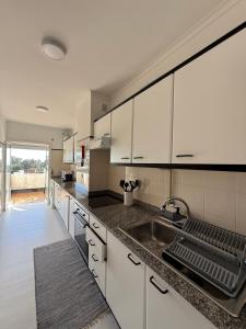 a kitchen with white cabinets and a sink at Beach House Cabedelo in Viana do Castelo
