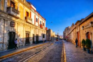 a city street with people walking on a cobblestone street at Hostal Violeta in Arequipa