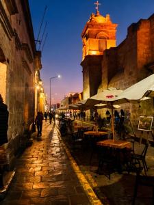 a street with tables and chairs and a clock tower at Hostal Violeta in Arequipa