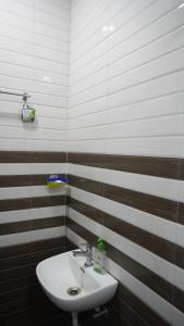 a white sink in a bathroom with brown and white stripes at Hotel Akshada & Guest House in Banda +81 photos