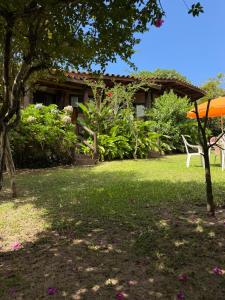 a yard with a house with an orange umbrella at Encanto do Mar Praia do Rosa in Praia do Rosa