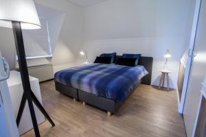 a bedroom with a bed with blue sheets and a lamp at Hotel-Restaurant Termunterzijl in Termunterzijl