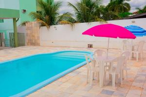 a table and chairs with an umbrella next to a pool at Novo Maanaim Hotel in Presidente Epitácio