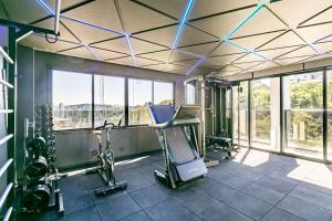 a gym with exercise equipment in a building with windows at Loft Completo com Piscina Aquecida 250m da Vila Germânica in Blumenau