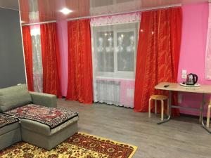 a living room with a couch and a table and red curtains at Apartments on pr. Lenina 7/42 in Monchegorsk