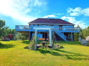 a blue house with a table and chairs in the yard at Panoramic Sunrise House in Terence Bay