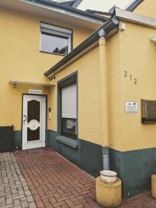 a yellow house with a white door and a brick driveway at STEP IN Apartments ! in Wilhelmshaven