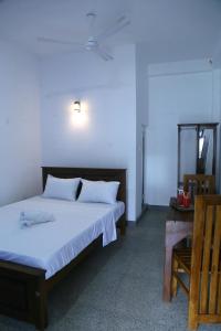 a bedroom with a large bed and a wooden chair at Emerald Coast Hotel Negombo in Negombo