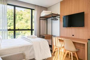 a bedroom with a bed and a desk and a television at Loft Completo com Piscina Aquecida 250m da Vila Germânica in Blumenau +19 photos