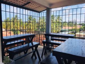 two tables and benches in a room with a large window at Emerald Coast Hotel Negombo in Negombo
