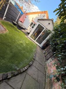 a backyard with a lawn and a house with a window at Cozy Cottage Coventry self check-in after 3pm, Pets Friendly in Longford