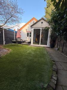a backyard with a lawn with a table and a chair at Cozy Cottage Coventry self check-in after 3pm, Pets Friendly in Longford