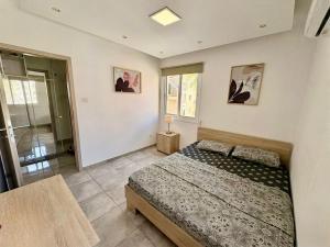 a bedroom with a bed and a table and windows at Jane 202 cosy 1 bedroom in Larnaca