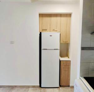 a white refrigerator in a kitchen with wooden cabinets at Jane 202 cosy 1 bedroom in Larnaca
