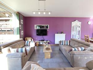 a living room with couches and a purple wall at Well Coom in Goé