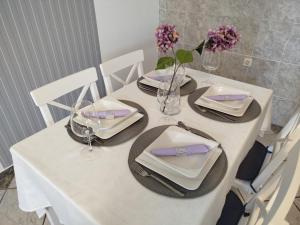 a white table with plates and glasses and flowers on it at Levendula Apartman in Bačka Topola
