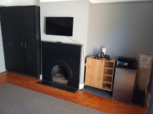 a living room with a fireplace with a tv above it at Wembley guesthouse in Plumstead