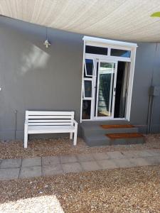 a white bench sitting in front of a door at Wembley guesthouse in Plumstead