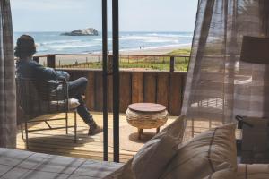 a woman sitting in a chair looking out at the beach at Hotel & Boulevard Pacífico in Matanzas