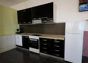 a kitchen with black cabinets and a white refrigerator at House Leon in Krujë +7 photos