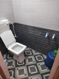 a bathroom with a toilet and a tiled floor at Swarna Lodge in Badami