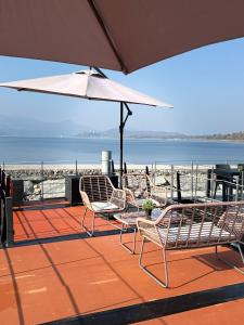 a patio with chairs and an umbrella and the beach at Floating Experience Black Pearl, Lago Maggiore in Dormelletto
