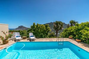 a swimming pool with two lawn chairs and a swimming pool at Seaview in Hout Bay