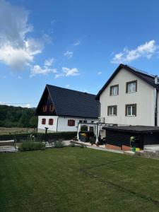 a white house with a black roof and a yard at B&B Millenium House 2 in Jezerce