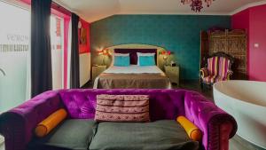 a purple couch in a room with a bed at L'écrin des Vennes - Liège centre in Liège