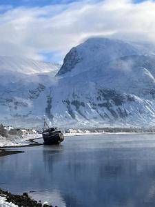 a boat sitting in the water in front of a mountain at Marys view in Fort William