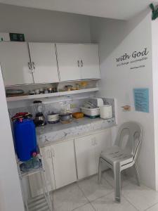 a kitchen with white cabinets and a chair in it at Metro Capsule Rental in Manila