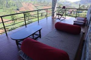a balcony with a bench and a table and a view at Rakas Guest House Ooty in Ketti