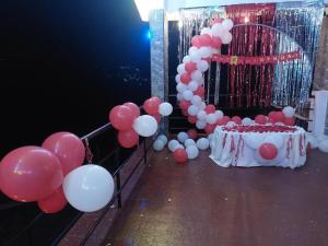 a bunch of balloons and a table with a cake at Rakas Guest House Ooty in Ketti