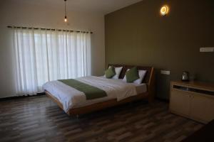a bedroom with a bed with green and white pillows at Rakas Guest House Ooty in Ketti