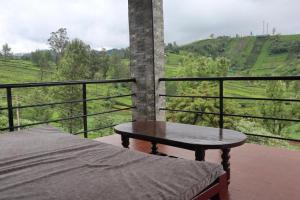 a bed and a table on a balcony with a view at Rakas Guest House Ooty in Ketti