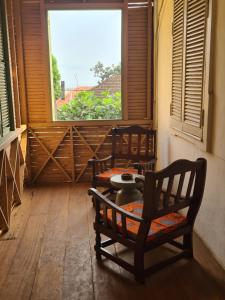 a room with two chairs and a table and a window at Chalé Quitxiba in São Tomé