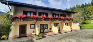a house with a balcony with pink flowers on it at Bergbauern Wirtshaus in Kötschach
