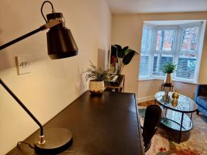 a living room with a table and a lamp at Stylish Spacious Serviced Apartment next to City Centre with Free Parking - Contractors & Relocators in Coventry
