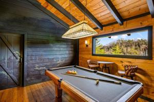 a pool table in a room with a window at Bearfoot Pines - True Log Cabin - Wi-Fi, Hot Tub, Fishing, Deck with views! - Mins to PF in Sevierville