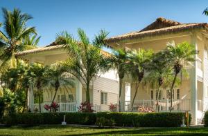 a large white house with palm trees in front of it at Azul Hotel & Retreat in Playa Azul